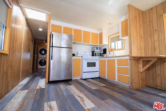 a kitchen with stainless steel appliances granite countertop a refrigerator a sink and wooden floors