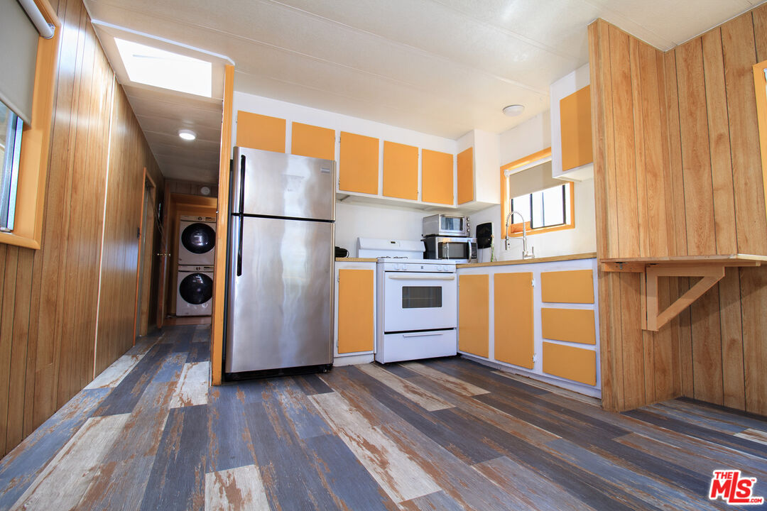 a kitchen with stainless steel appliances granite countertop a refrigerator a sink and wooden floors