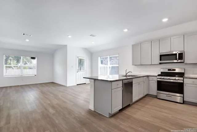 a kitchen with stainless steel appliances granite countertop a stove a sink and a microwave