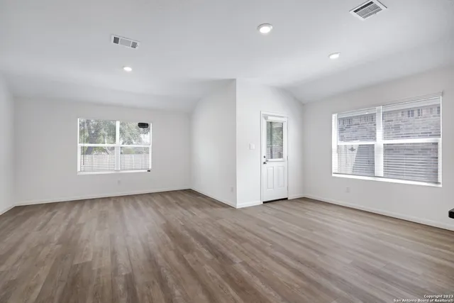 a view of an empty room with wooden floor and a window