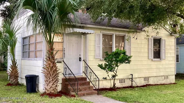a view of house with a yard and potted plants