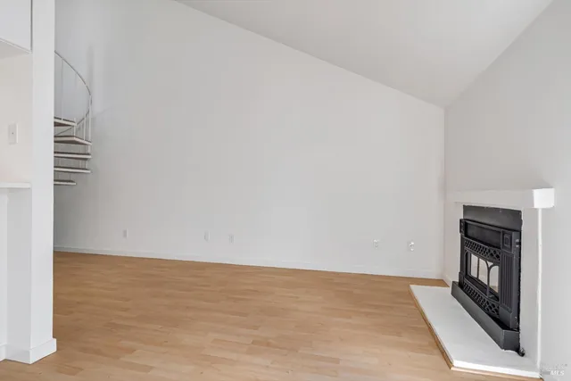 a view of an empty room with wooden floor and a fireplace