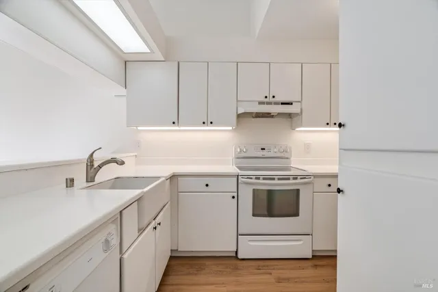 a kitchen with granite countertop white cabinets and white appliances