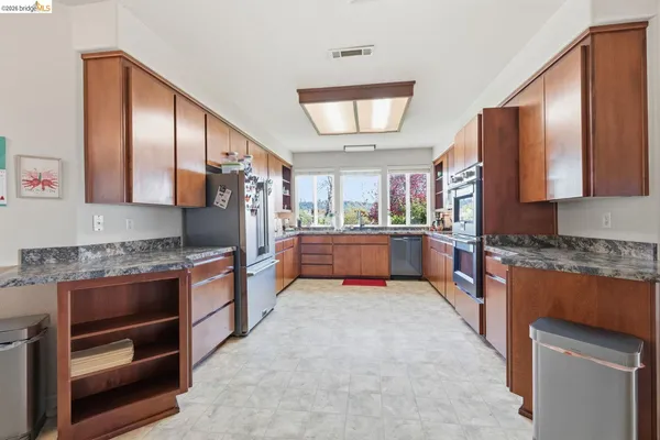 a large kitchen with stainless steel appliances granite countertop a stove refrigerator and cabinets