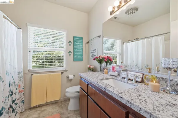 a bathroom with a granite countertop sink a toilet and a large mirror