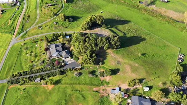 a aerial view of a house with a yard and large trees