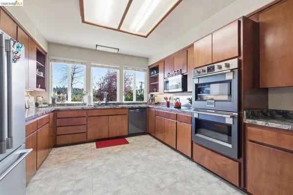 a kitchen with stainless steel appliances granite countertop a stove refrigerator and cabinets