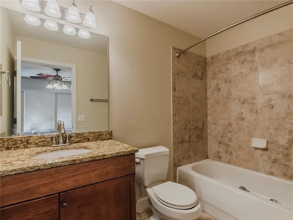 a bathroom with a granite countertop sink a toilet and shower