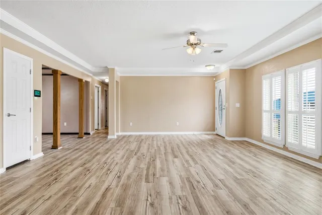 a view of an empty room with wooden floor and a window
