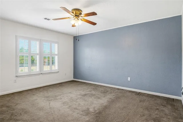an empty room with a window and a fan