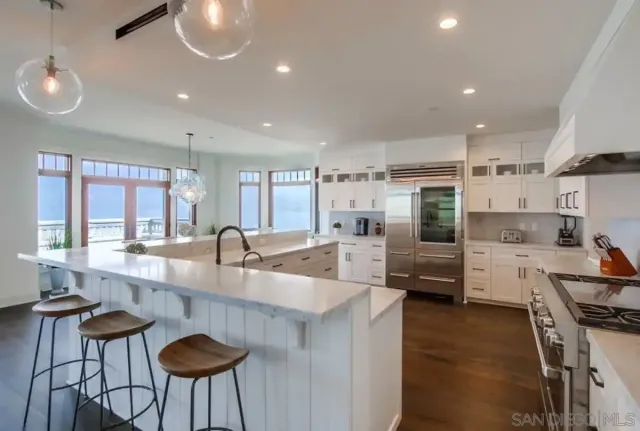 a large kitchen with kitchen island a large counter top space a sink stainless steel appliances and cabinets