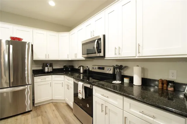 a kitchen with granite countertop a sink stainless steel appliances and cabinets