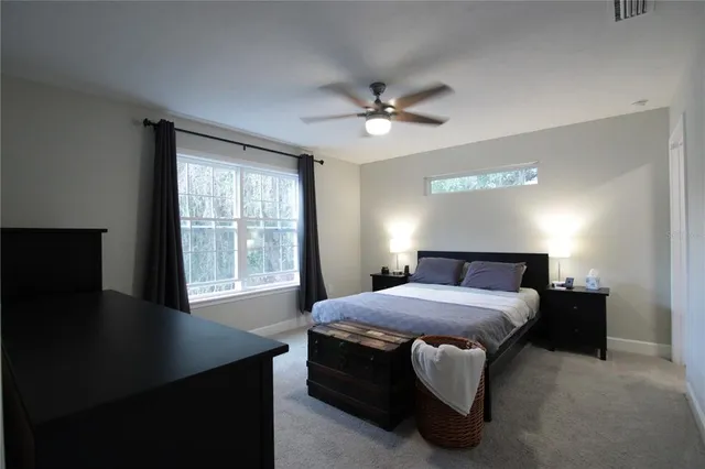 a bedroom with a bed chandelier and a window