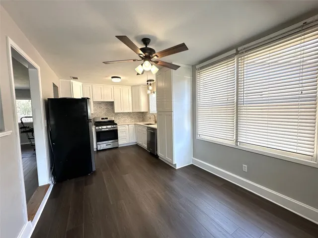 a kitchen with stainless steel appliances a refrigerator a sink dishwasher a stove and white cabinets with wooden floor