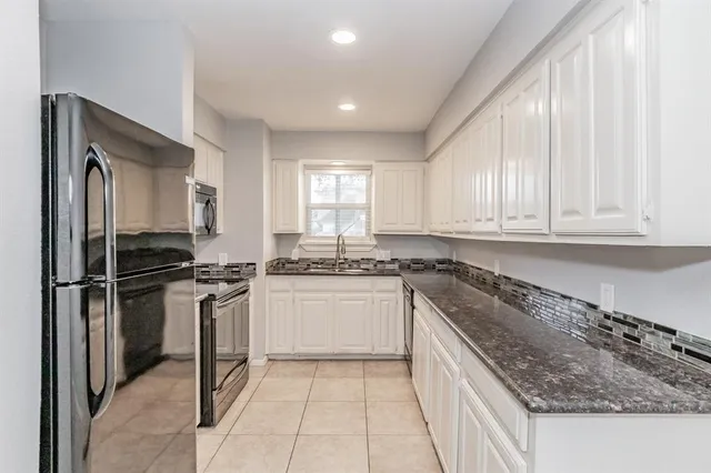 a kitchen with granite countertop white cabinets and white appliances