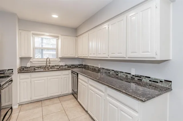 a kitchen with granite countertop a refrigerator stove and sink