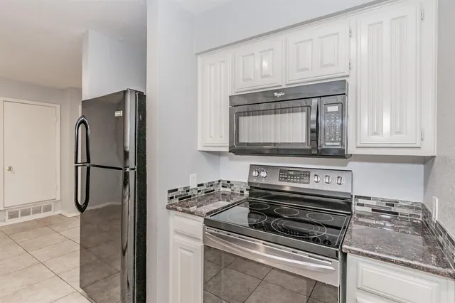 a kitchen with granite countertop white cabinets and stainless steel appliances