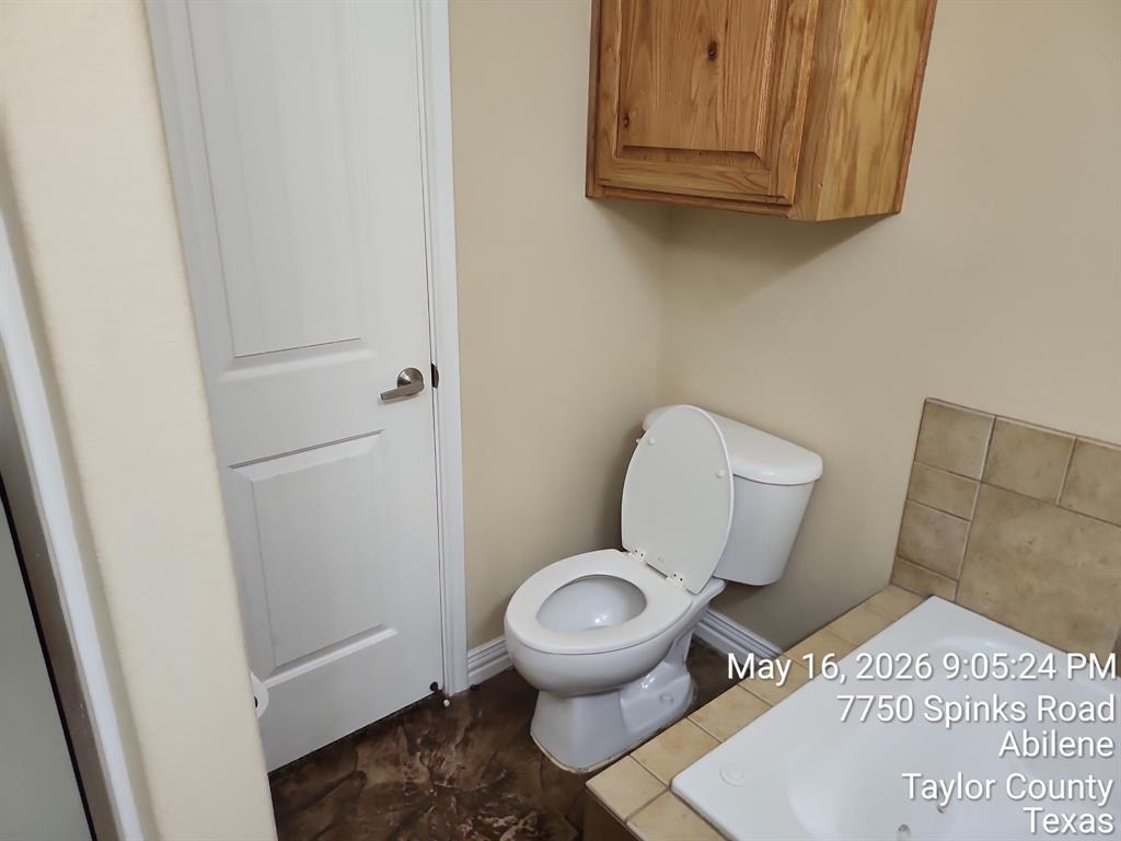 7750 Spinks Road Abilene, TX 79603 - Photo 12 of 15 a white toilet sitting next to a wooden cabinet