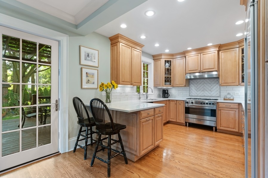 727 Indian Road Glenview, IL 60025 - Photo 8 of 58 a kitchen with kitchen island granite countertop wooden floors and stainless steel appliances