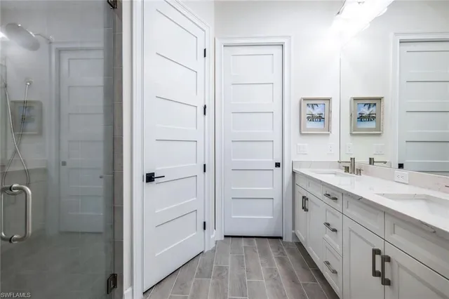 a spacious bathroom with a double vanity sink a mirror and a shower