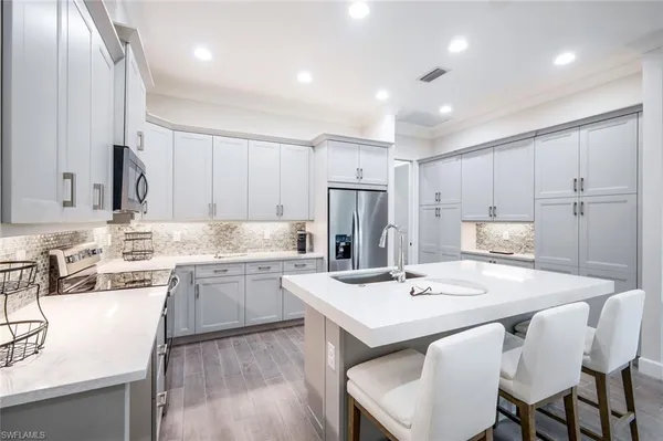 a kitchen with a sink stools a counter space and cabinets