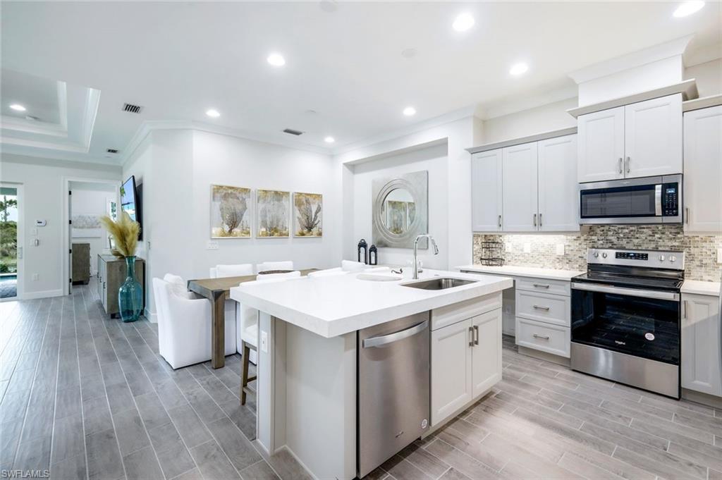 6875 Saona Court Naples, FL 34113 - Photo 6 of 21 a kitchen with a sink stove and refrigerator