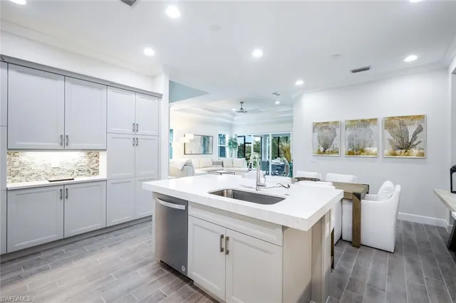 a kitchen with a sink cabinets wooden floor and stainless steel appliances