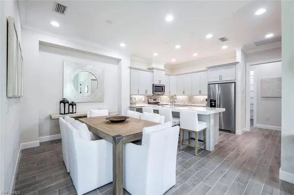 a kitchen with stainless steel appliances granite countertop a table chairs a sink and a refrigerator
