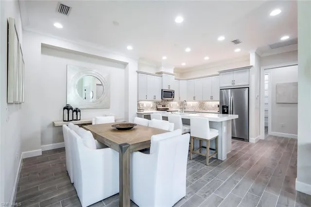 a kitchen with stainless steel appliances granite countertop a table chairs a sink and a refrigerator