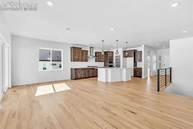 a view of a living room kitchen with stainless steel appliances wooden floor dining table and chair