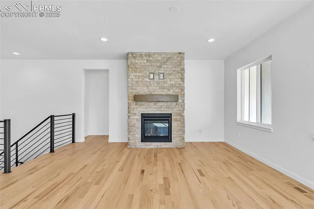 a view of empty room with wooden floor and fireplace