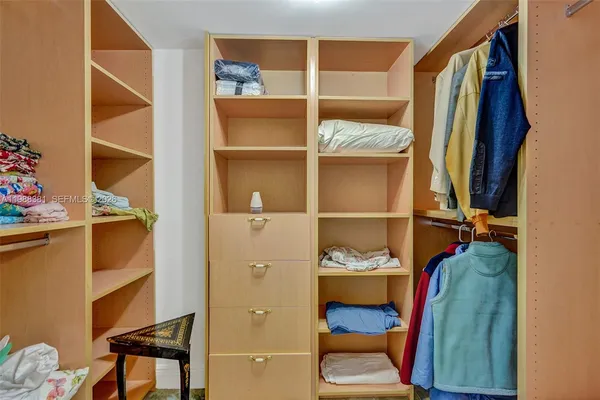 a view of walk in closet with clothes and shoes