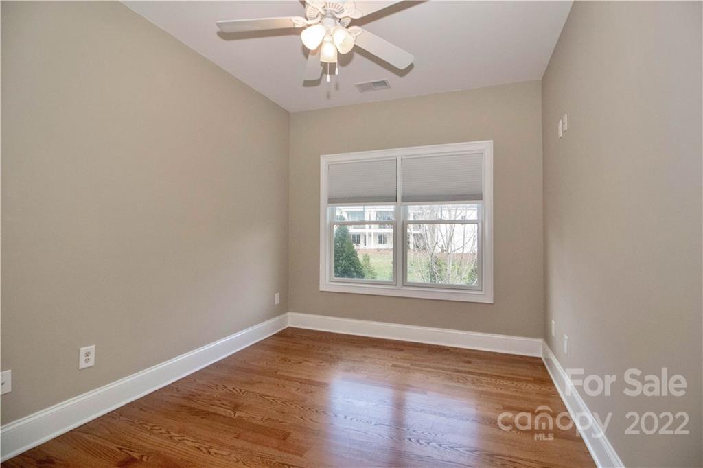 333 Spring Street Davidson, NC 28036 - Photo 30 of 44 an empty room with wooden floor chandelier fan and windows