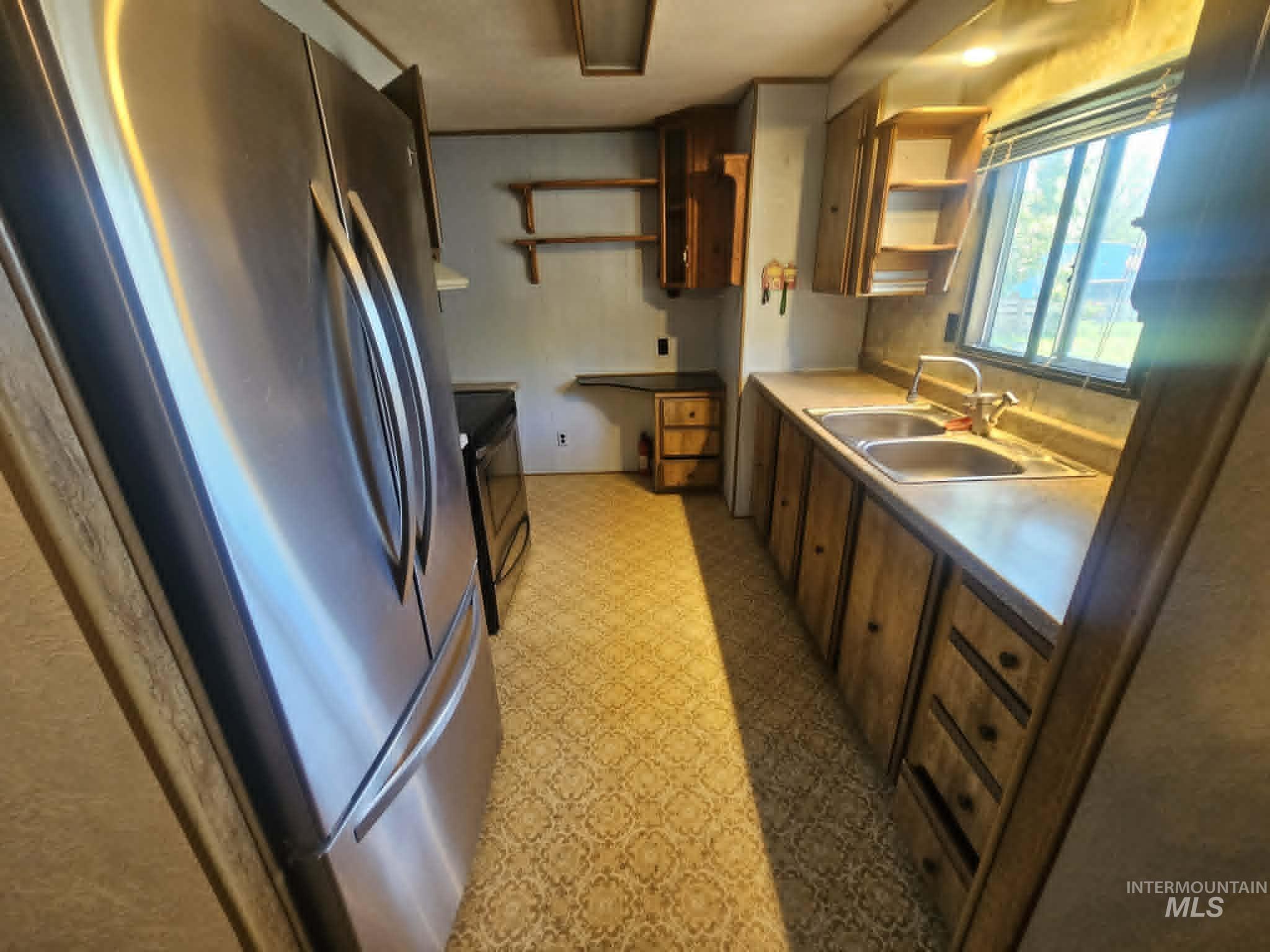 461 Greenleaf Street Boise, ID 83713 - Photo 10 of 19 Kitchen featuring stainless steel refrigerator, double basin sink with chrome faucet, wood-finish cabinetry, and patterned flooring