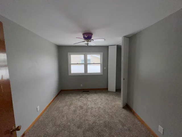 an empty room with windows and chandelier fan