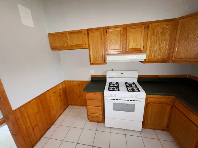 a kitchen with granite countertop a sink a stove and cabinets