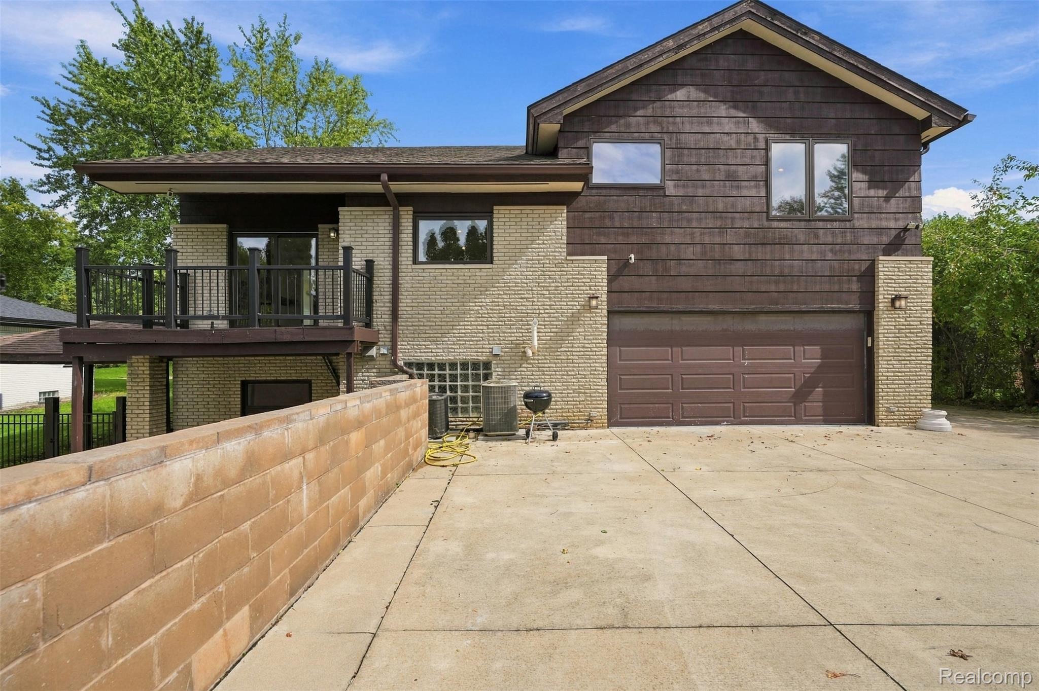 27507 Bell Road Southfield, MI 48034 - Photo 56 of 81 Two-story dwelling with brick and horizontal siding, an attached garage, a concrete driveway, a retaining wall, and an upper-level balcony with dark railings