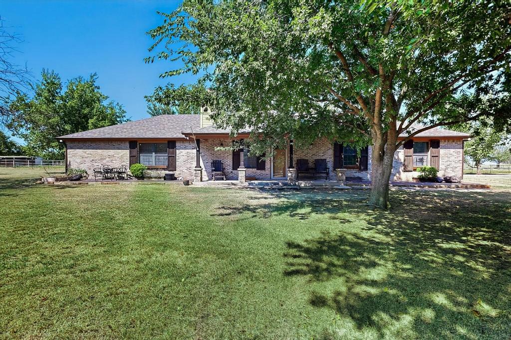 Back of house with brick siding, a yard, a patio, and a chimney