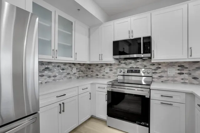 a kitchen with stainless steel appliances white cabinets and a stove top oven