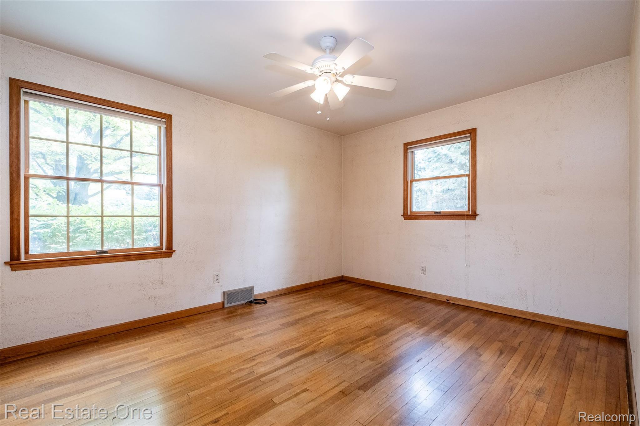 11030 Marshall Road South Lyon, MI 48178 - Photo 37 of 83 Bright, generously proportioned room featuring gleaming wood-finish flooring, abundant natural light from dual wood-framed windows, and a ceiling fan with integrated lighting