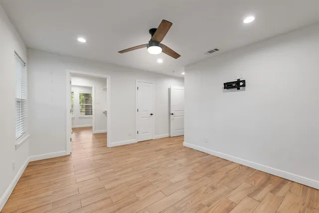 an empty room with wooden floor and windows