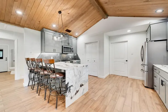 a kitchen with stainless steel appliances a dining table chairs stove and refrigerator
