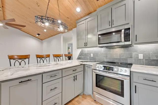a kitchen with granite countertop stainless steel appliances a stove microwave and cabinets