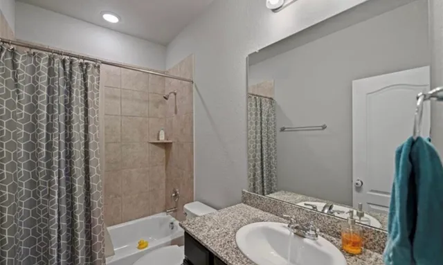 a bathroom with a granite countertop sink a mirror a bathtub and shower