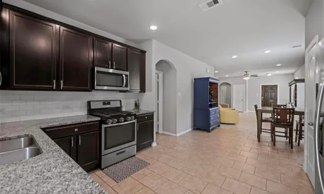 a kitchen with stainless steel appliances granite countertop a stove a sink a microwave a refrigerator and cabinets