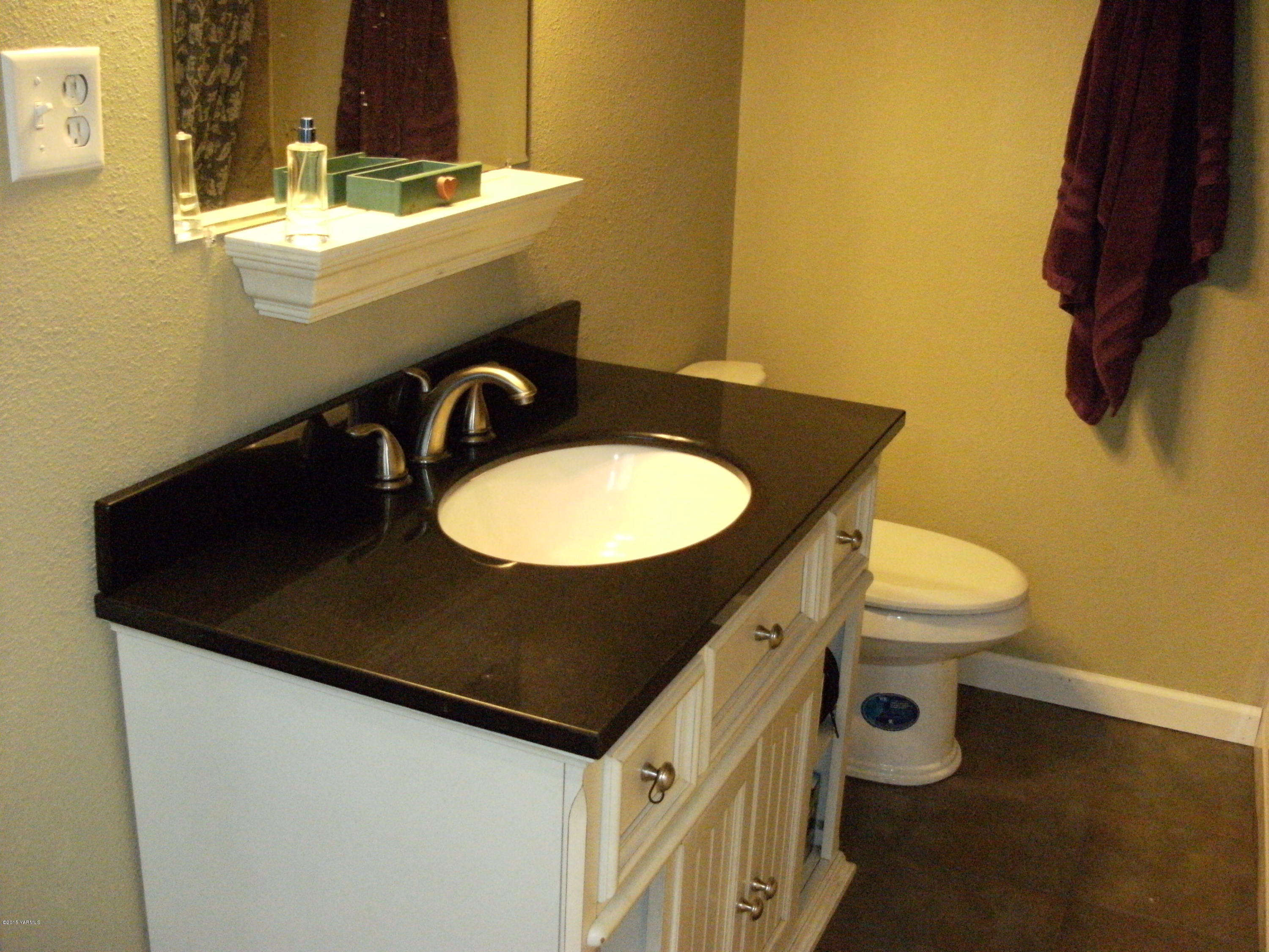 1180 Woodworth Road Grandview, WA 98930 - Photo 12 of 26 a bathroom with a sink a toilet and mirror