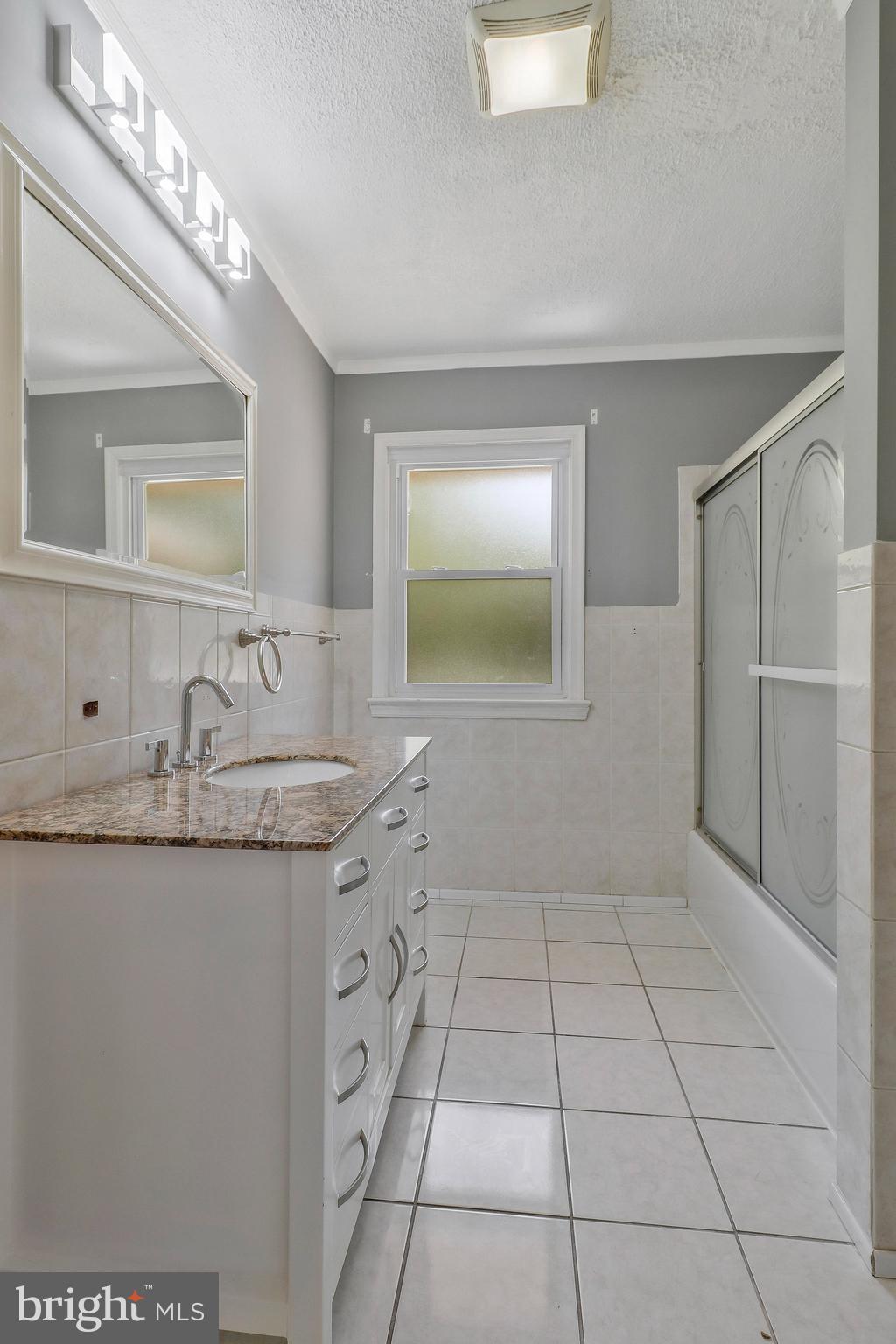9600 Woodland Avenue Lanham, MD 20706 - Photo 15 of 41 a bathroom with a granite countertop sink a mirror and a shower