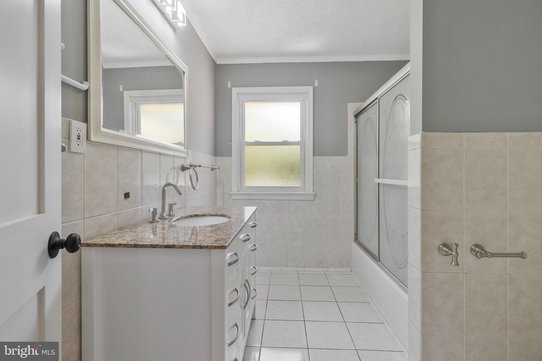 9600 Woodland Avenue Lanham, MD 20706 - Photo 16 of 41 a bathroom with a granite countertop sink a mirror and shower
