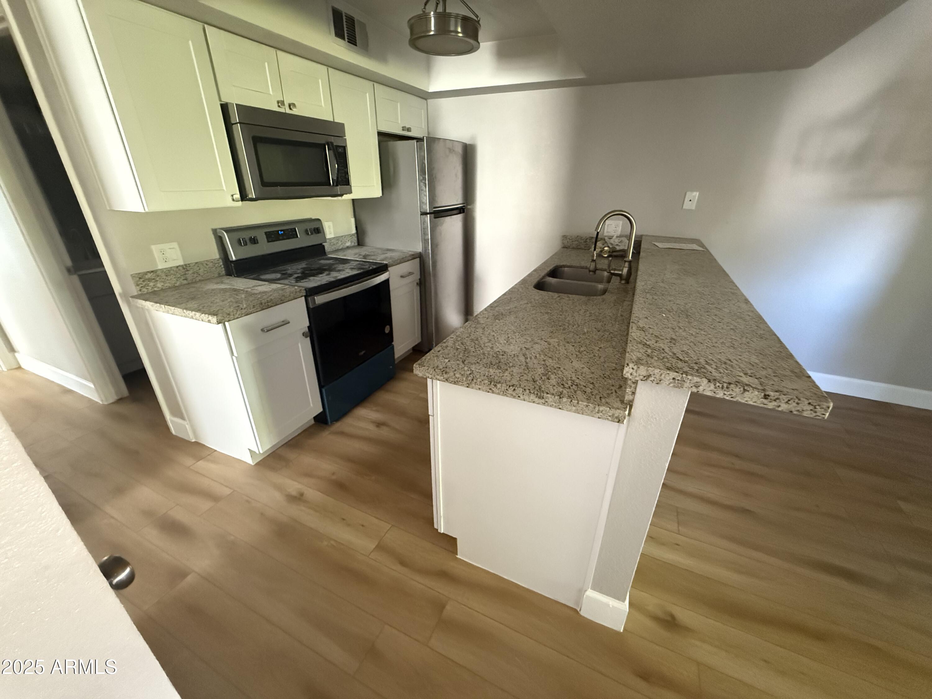 8801 North 8th Street, Unit 203 Phoenix, AZ 85020 - Photo 13 of 29 a kitchen with stainless steel appliances granite countertop a stove a microwave and a sink