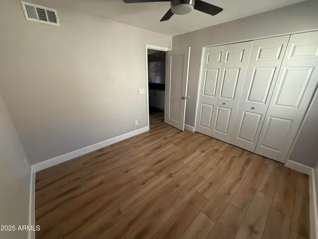 a view of a room with wooden floor and a ceiling fan